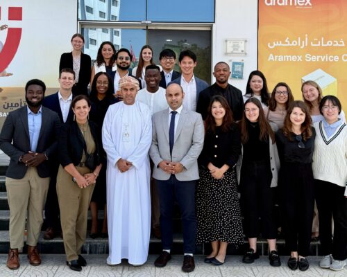 A group of diverse, professionally dressed individuals standing together outside a building, indicating a business or educational gathering.