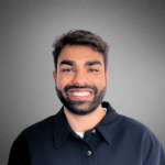 Ravi Patel_ Headshot of person smiling with a dark shirt against a neutral background.